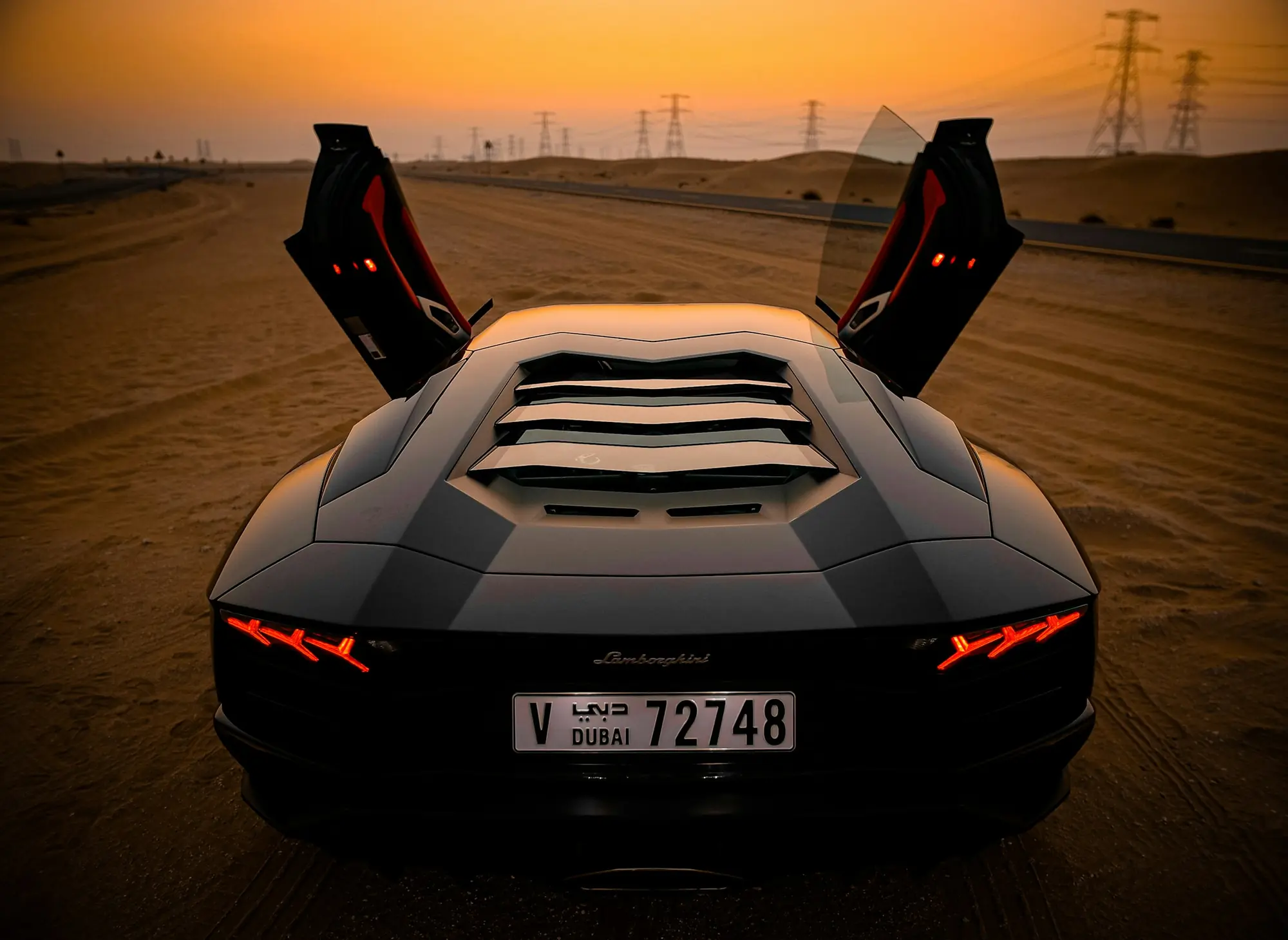 Lamborghini Aventador with its doors up on a Dubai road at dusk